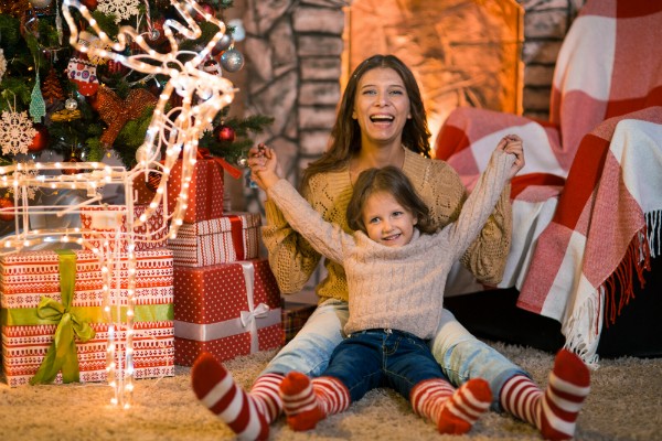 Kleines Maedchen mit Mutter im dekorierten Wohnzimmer zu Weihnachten