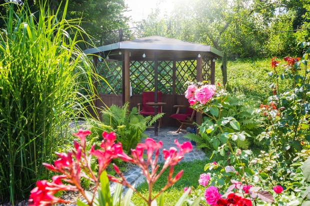 Gartenpavillon umgeben mit Grünpflanzen und Blumen -den Gartenpavillon gestalten ist wichtig