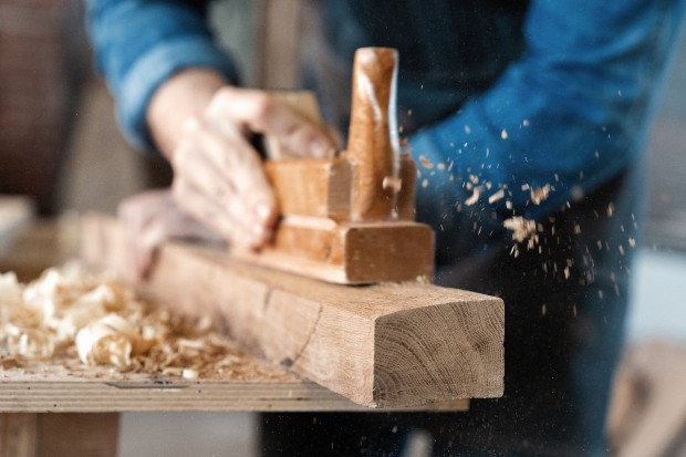 Mann hobelt ein Holzstück