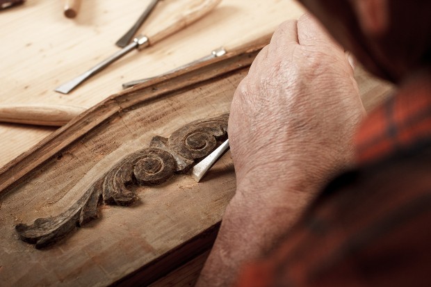 Ein Tischler arbeitet an dem Ornament eine Holzmöbels