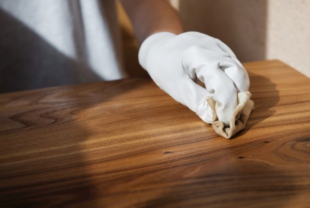 Hand bringt Holzwachs auf