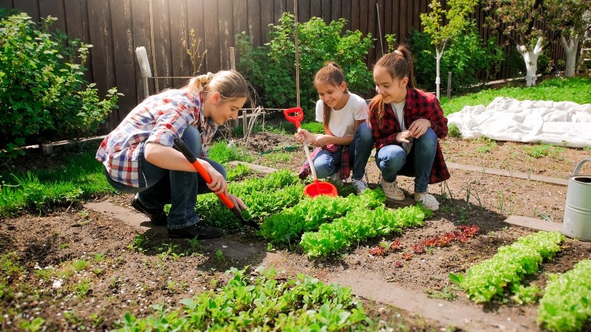 Frau mit 2 Töchtern bei der Gartenarbeit - Gartenbeet dekorieren und einrichten