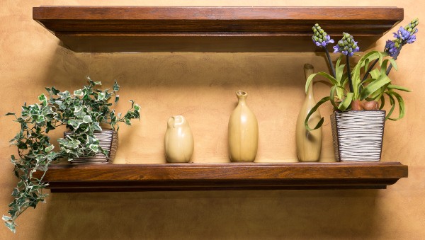 In einem Wandregal sind mehrere Vasen und zwei Pflanzen platziert