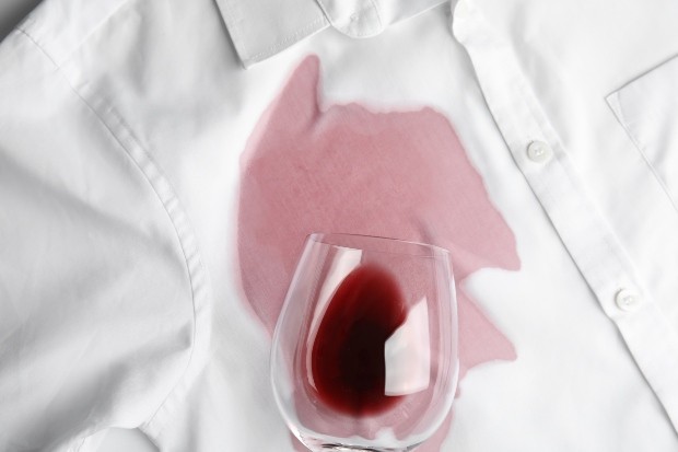 Rotweinglas liegt umgekippt auf weißem Hemd