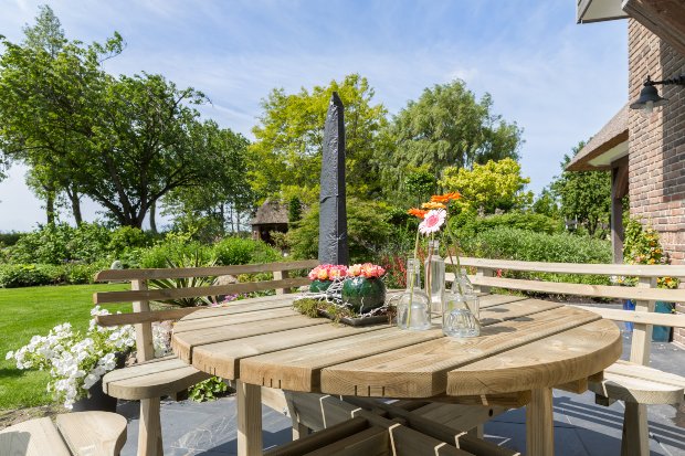 Eine Gartenmöbelgarnitur bestehend aus Tisch und zwei Bänke ist in einem schönen Garten positioniert
