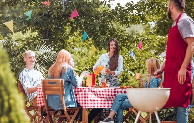 Junge Leute sitzen am Tisch, Grillplatz im Garten