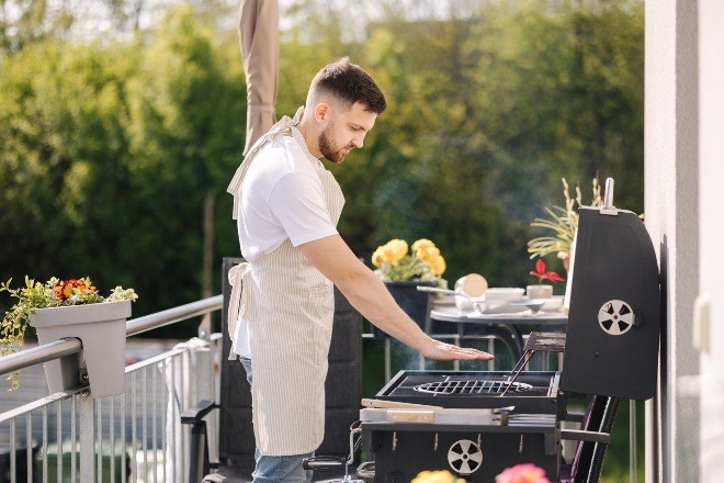 Mann-grillt-auf-Balkon - Grillecke einrichten