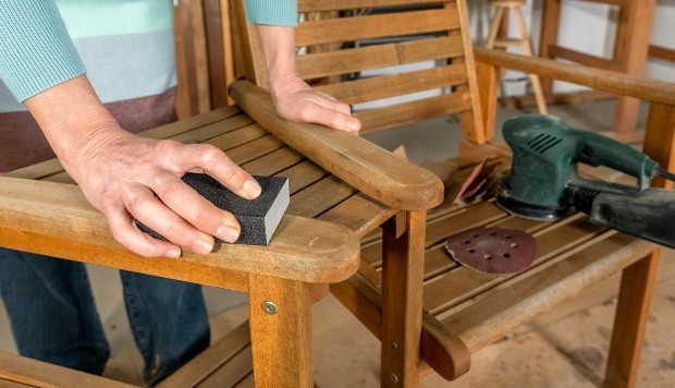 Frau schleift Stuhl mit Schleifpapier ab - Holzmöbel aufhellen