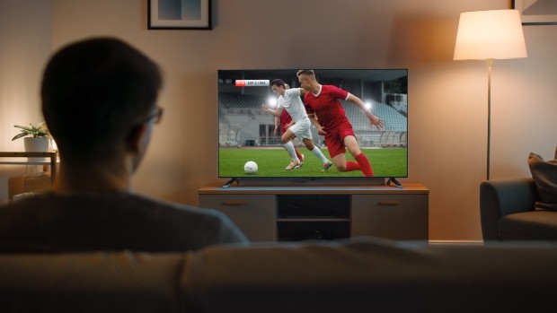 Junger Mann schaut Fussball im Fernsehen - TV-Wand - Ideen für den Fernseher