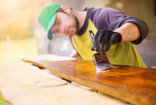 Mann trägt Holzwachs mit Pinsel auf